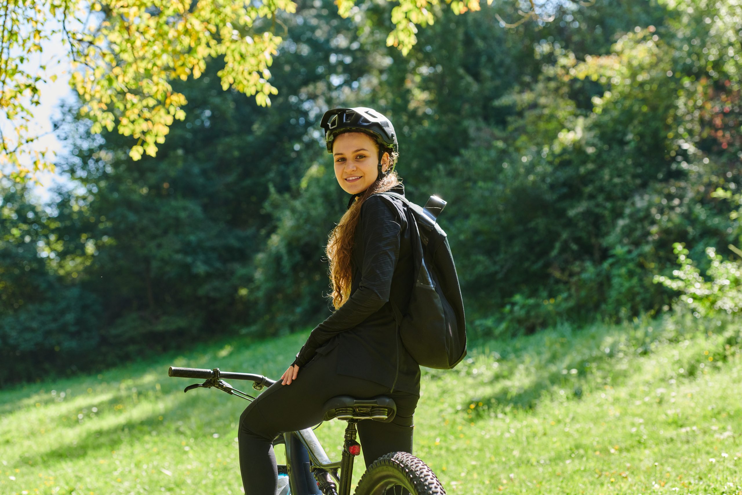In the radiant embrace of a sunny day, a joyous girl, adorned in professional cycling gear, finds pure bliss and vitality as she cruises through the park on her bicycle, her infectious laughter echoing the carefree harmony of the moment.