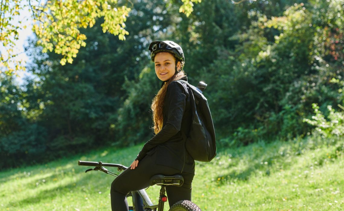 In the radiant embrace of a sunny day, a joyous girl, adorned in professional cycling gear, finds pure bliss and vitality as she cruises through the park on her bicycle, her infectious laughter echoing the carefree harmony of the moment.